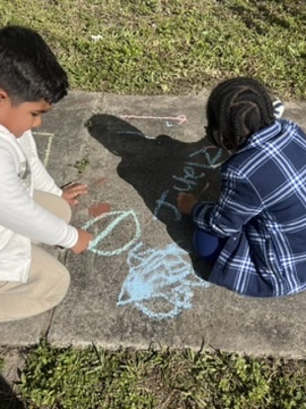 kids outside playing with chalk on the sidewalk